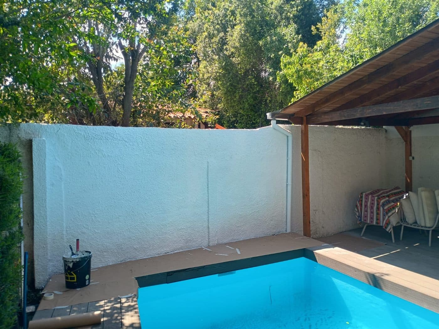 La misma muralla del patio ya reparada y pintada de blanco, junto a la piscina