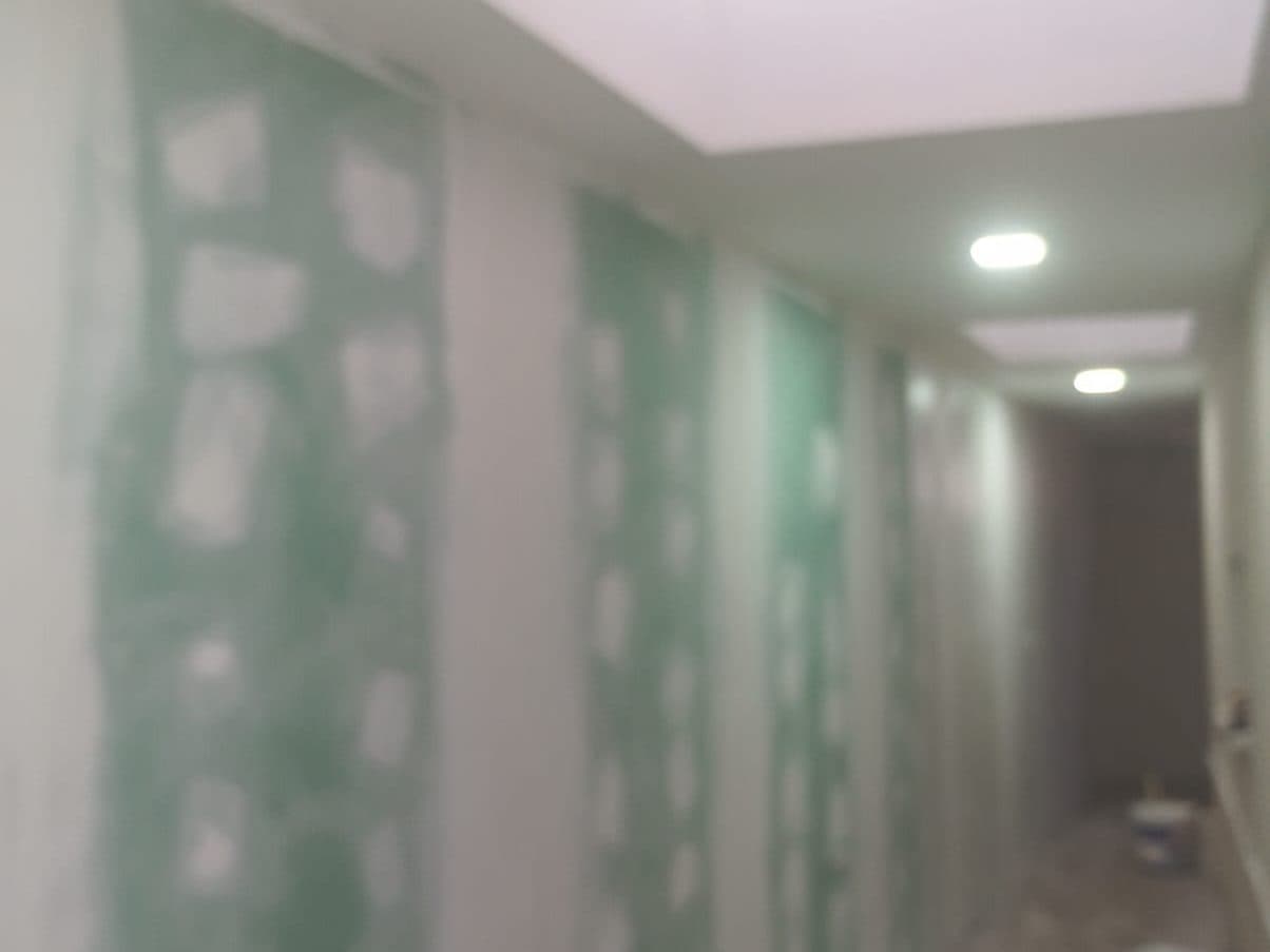Pasillo con los muros empastados por partes, antes de pintar