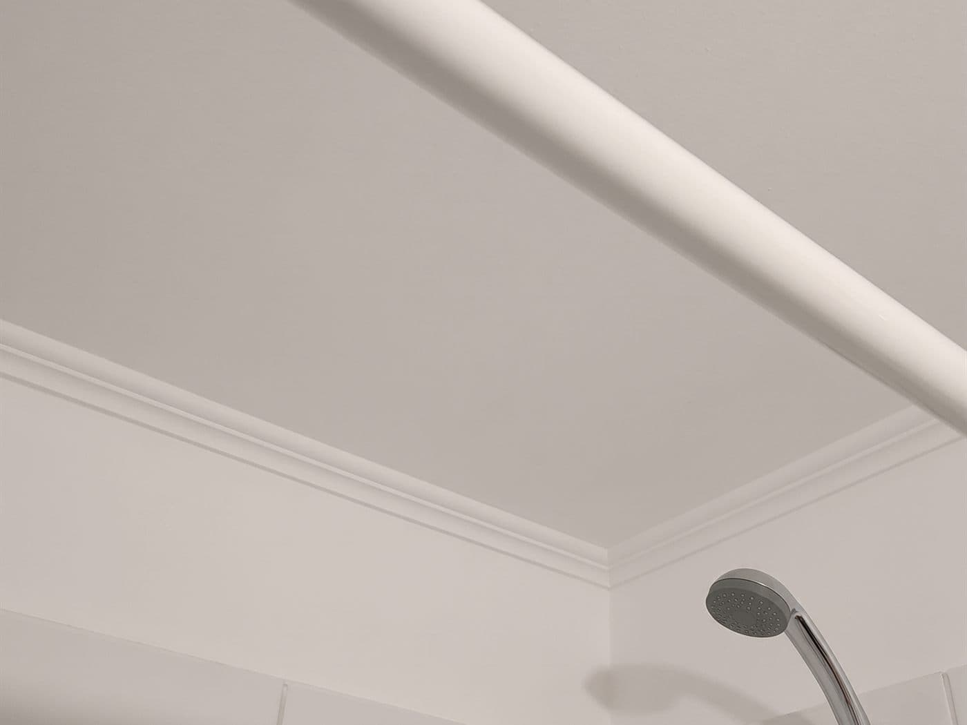 El mismo cielo de baño ya pintado de blanco, con la cornisa y la barra de la cortina de ducha